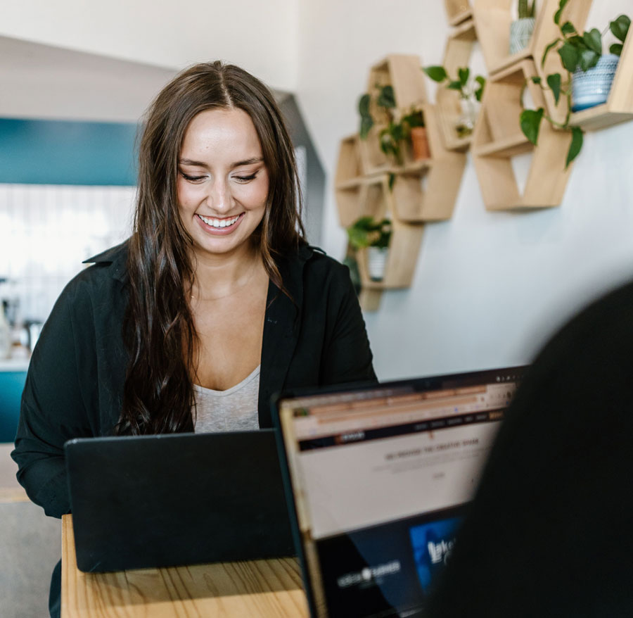 Woman smiling while using a laptop at cafe