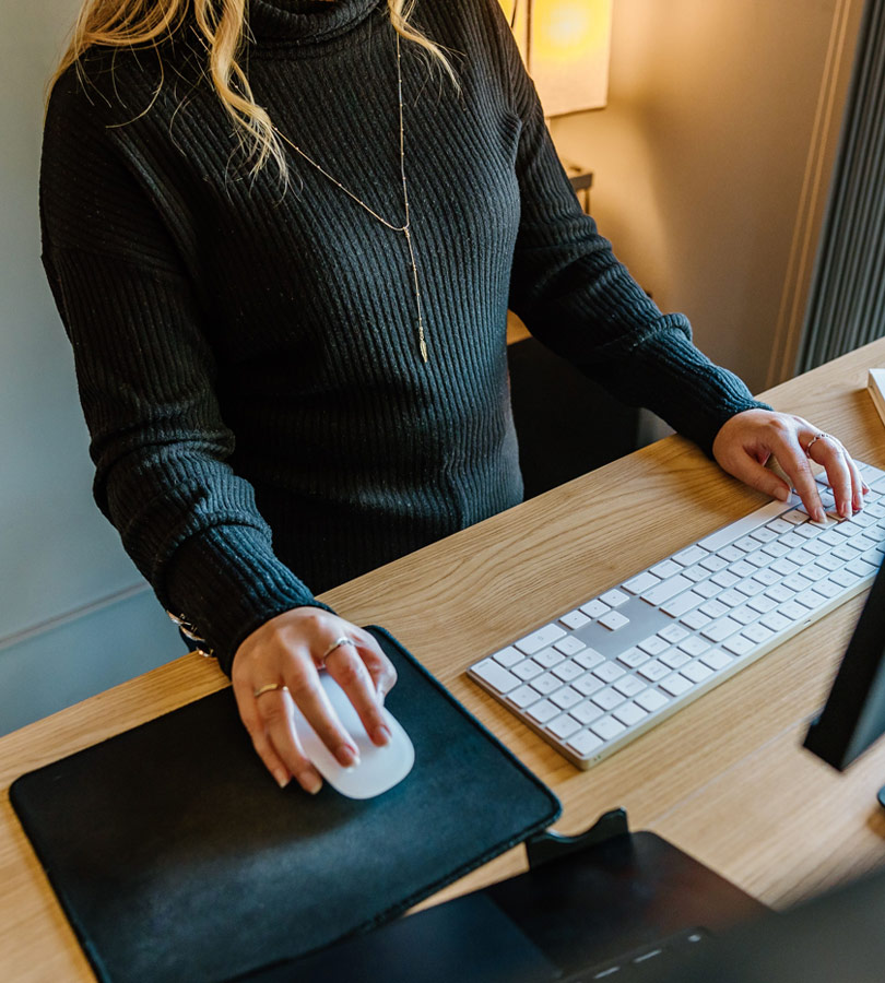 Person using computer mouse and keyboard at desk.